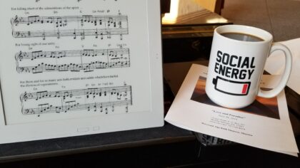 "Social Energy" coffee mug next to the sheet music for "We Begin Again in Love"